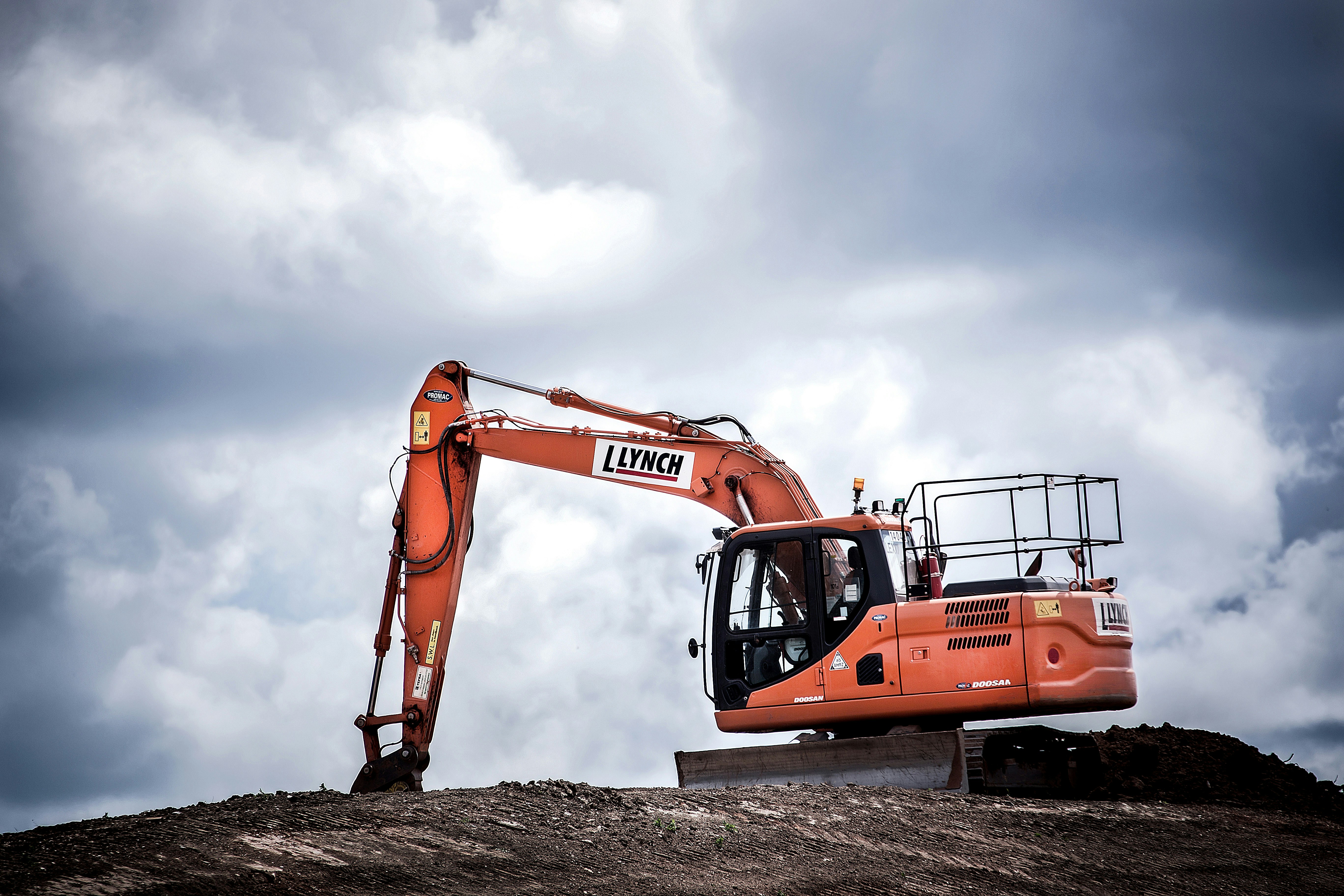 orange construction equipment operating on jobsite with brown dirt