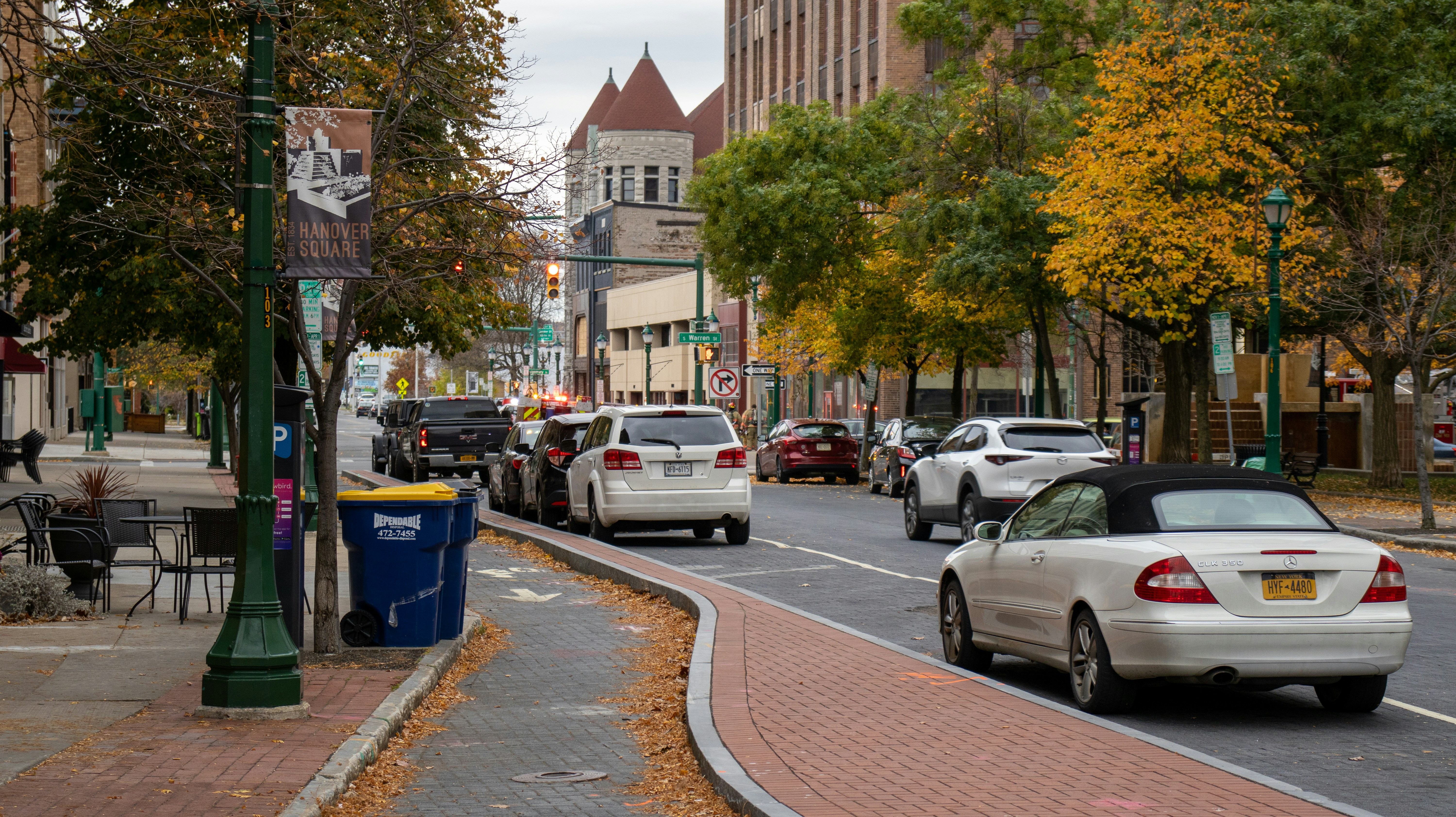 ALT= Debt Collection Agency Syracuse New York + downtown new york + fall setting + yellow orange trees + cars on the road