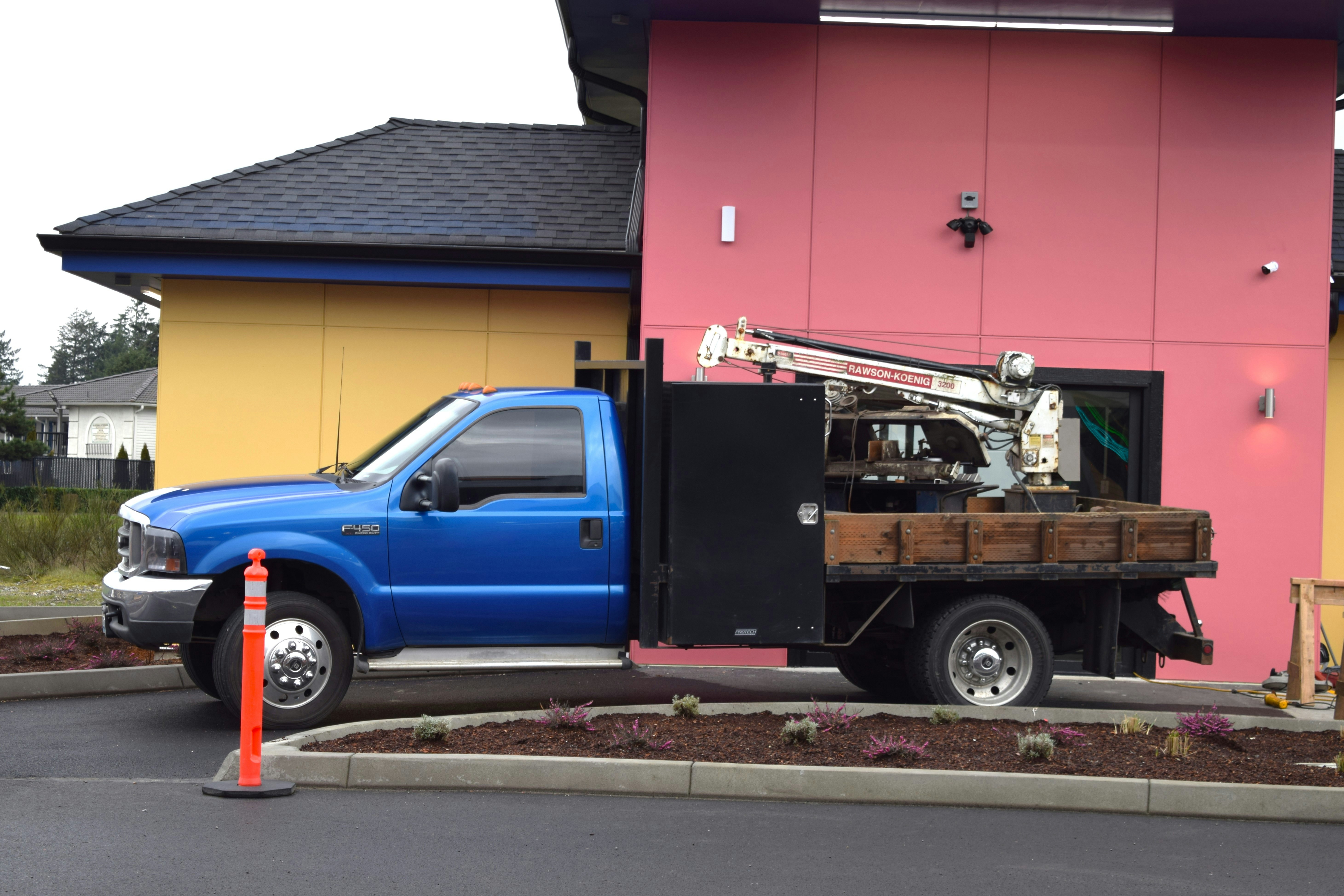 blue work truck infront of a yellow and pink building