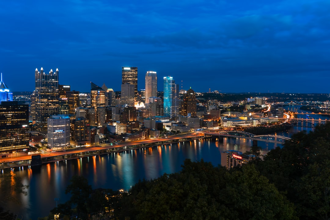 ALT= Debt Collection Agency in Pittsburgh PA + night picture + downtown Pittsburgh + longshot + buildings light up + river + green trees