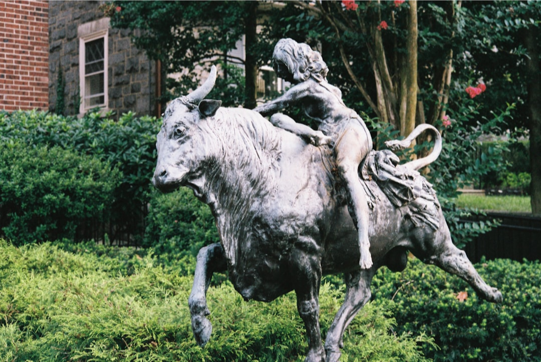 ALT= Debt Collection Agency in Jersey City NJ + famous statue in Jersey City of man riding bull + bushes in the background
