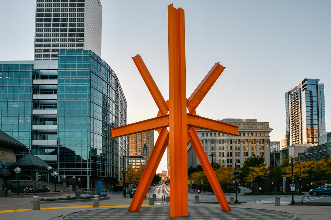 ALT= Debt Collection Agency in Milwaukee Wisconsin + buildings in downtown Milwaukee + famous orange art structure in Milwaukee + sunset